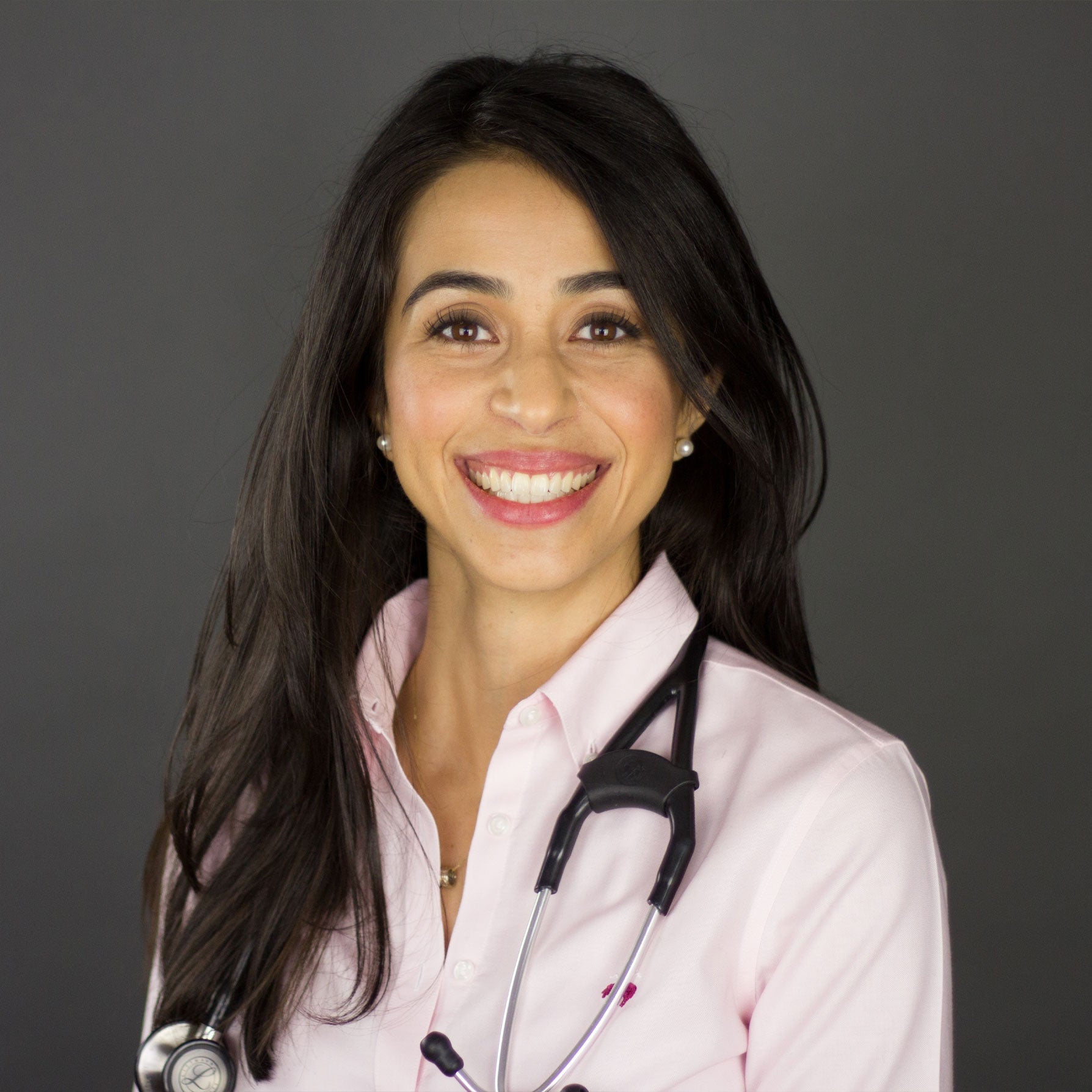 Photo of Dr. Olica Trejo, wearing a pink button up shirt with a stethoscope over her shoulders
