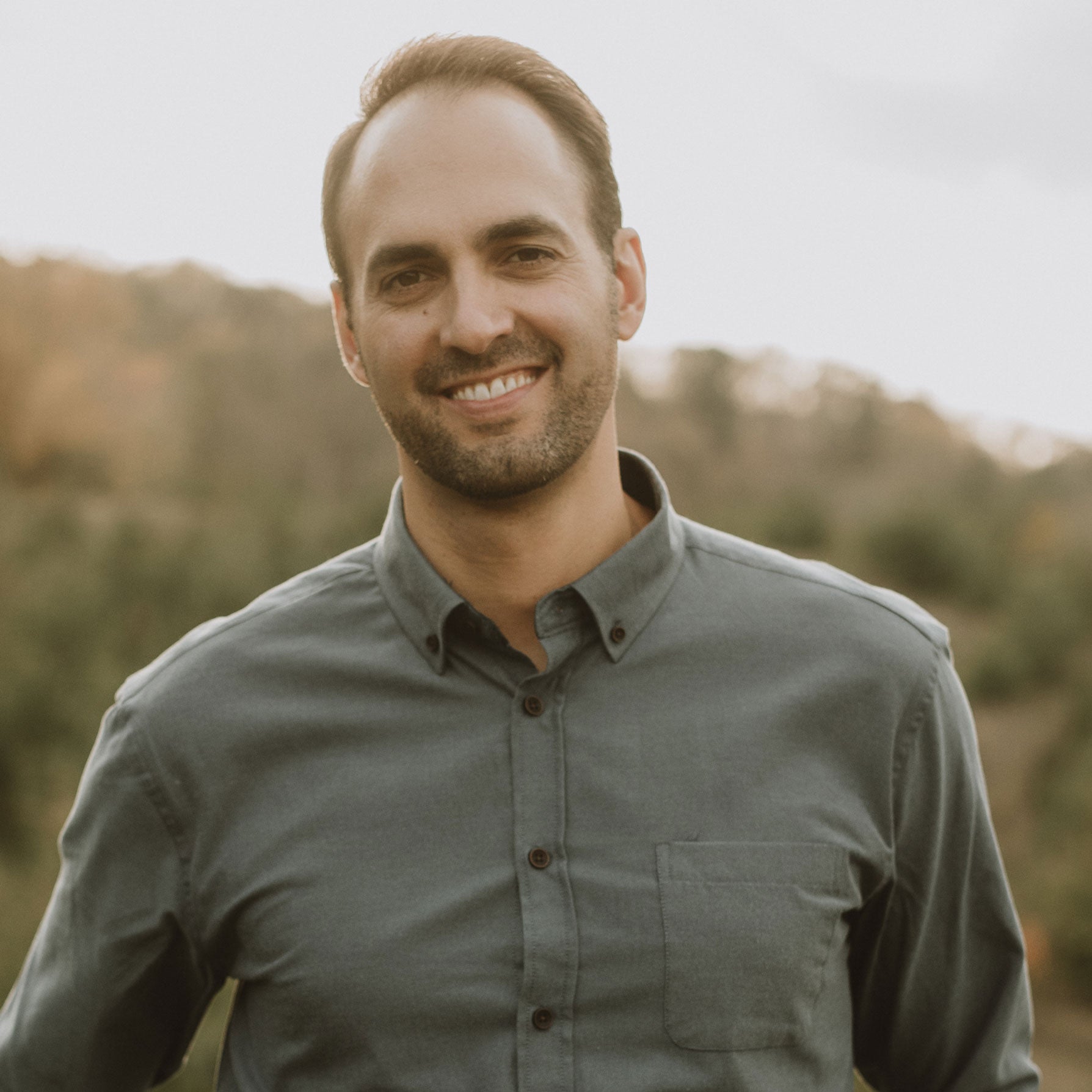 Photo of Dr. Paul Hrkal wearing a green button up, looking to lens and smiling