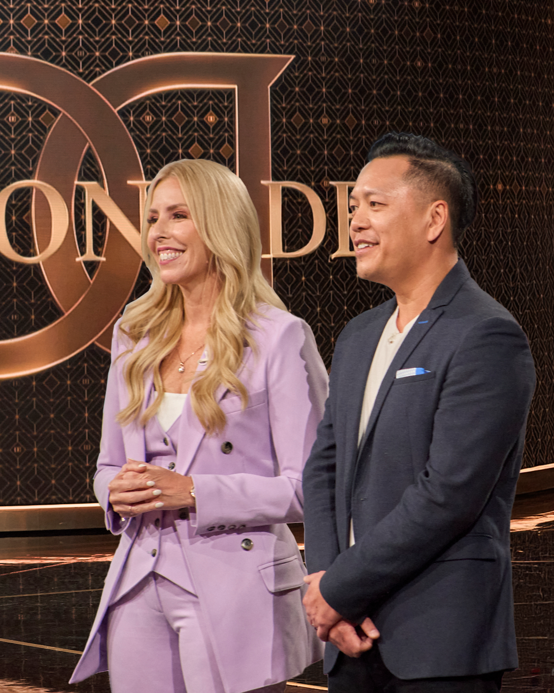 Gina Livy and Tony An standing in front of a 'Dragon Den' logo on a dark background