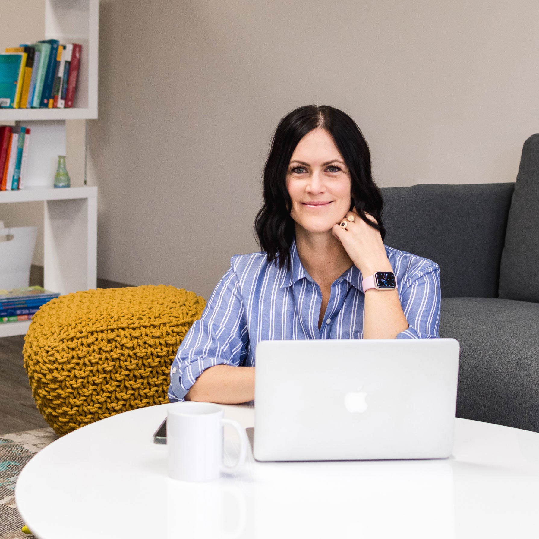 Photo of Dr. Beverley David sitting at a laptop, looking to camera and smiling