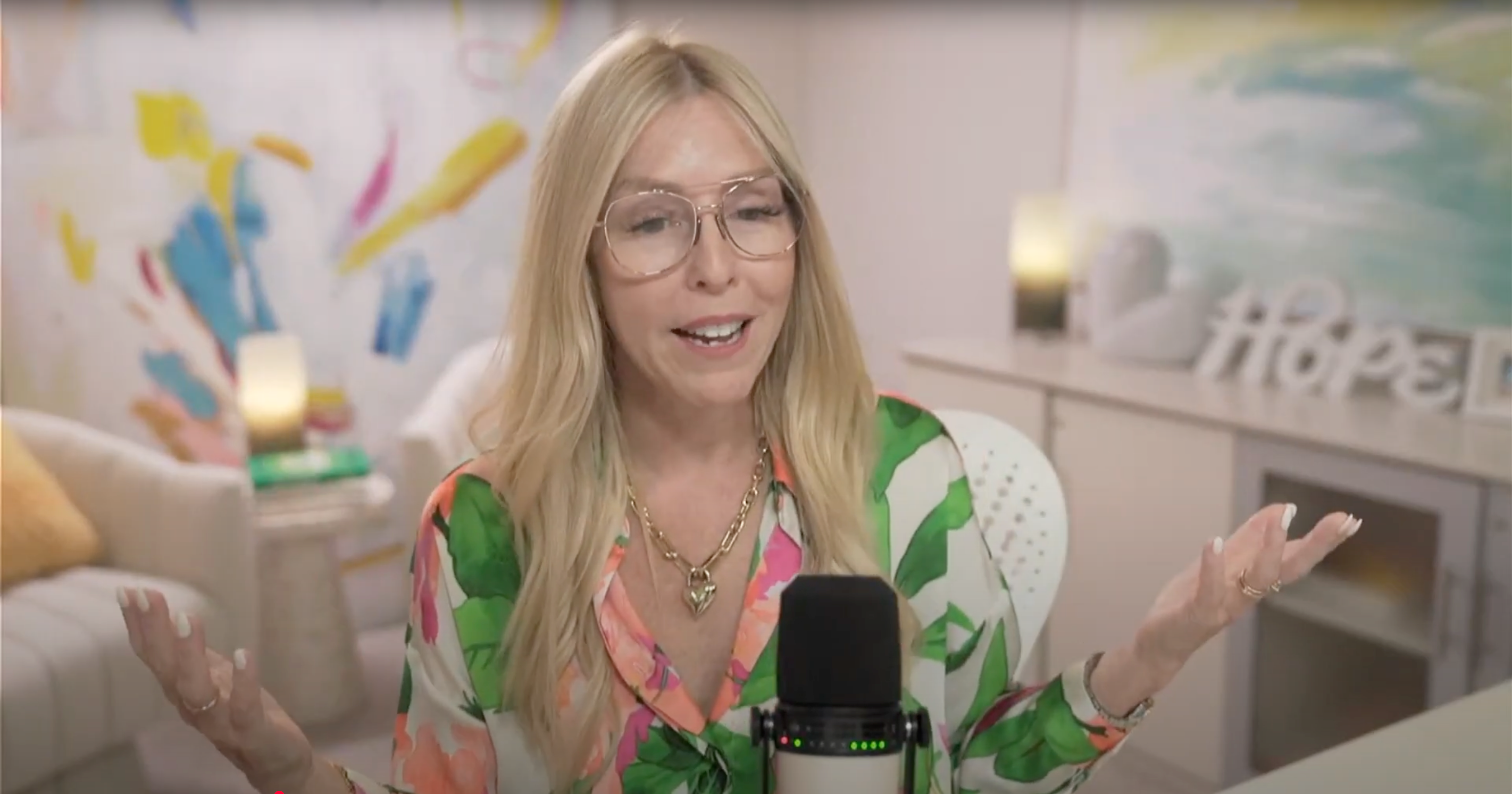 Gina addresses her members from her home studio wearing a floral blouse